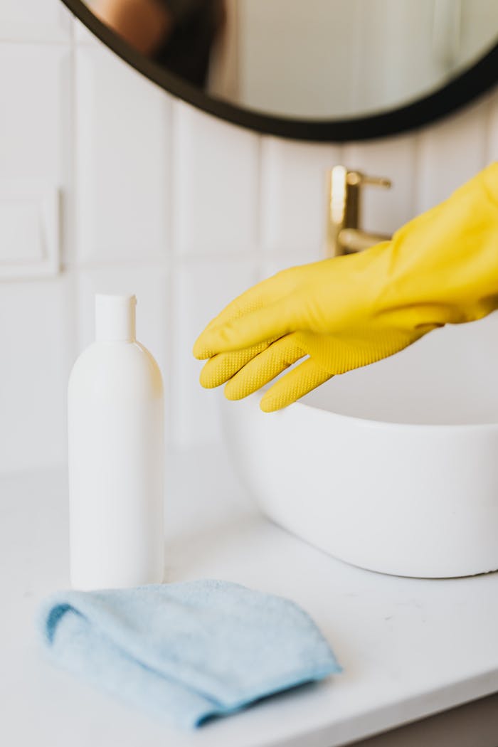 Yellow gloves and cleaning supplies in a modern bathroom setting.